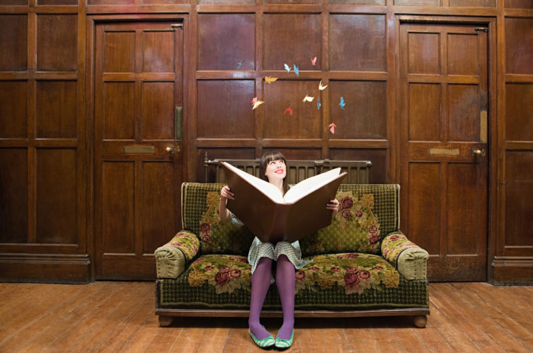 A teenage girl reading a large book